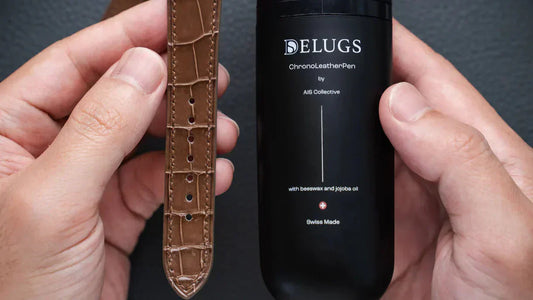 Two hands holding a Delugs ChronoPen by AIS Collective and a Delugs tan leather strap