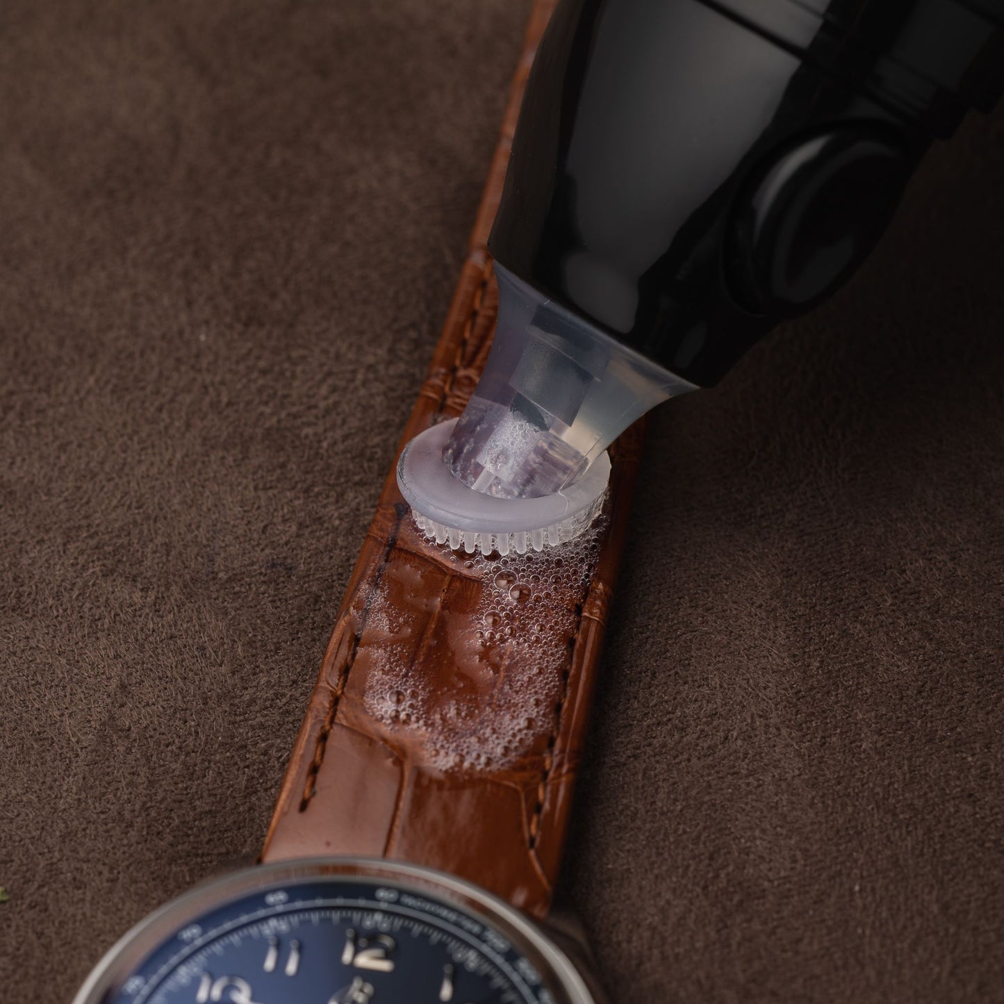 Applying the specialized conditioning formula of the ChronoLeatherPen directly onto a brown alligator leather strap or a Breitling watch.