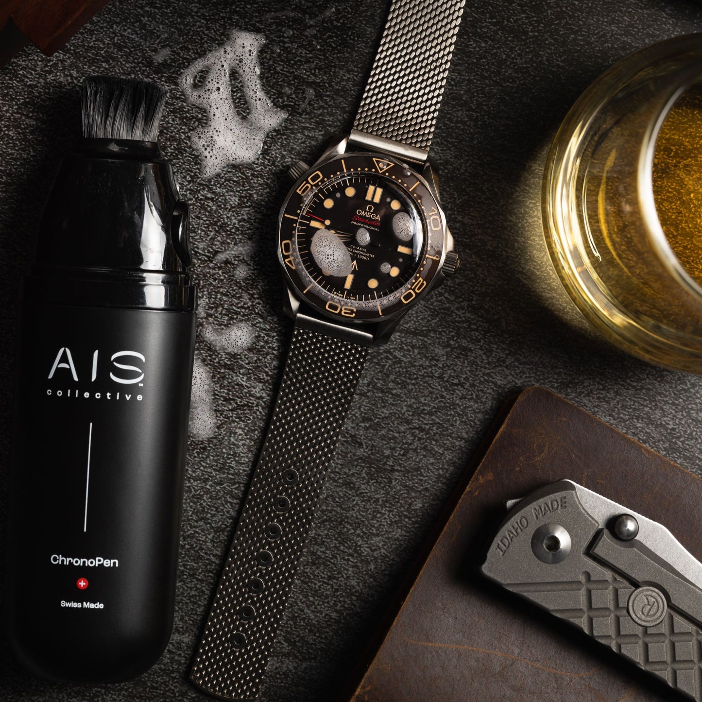 Flat lay of luxury watch accessories, including an Omega watch alongside the AIS Collective ChronoPen.