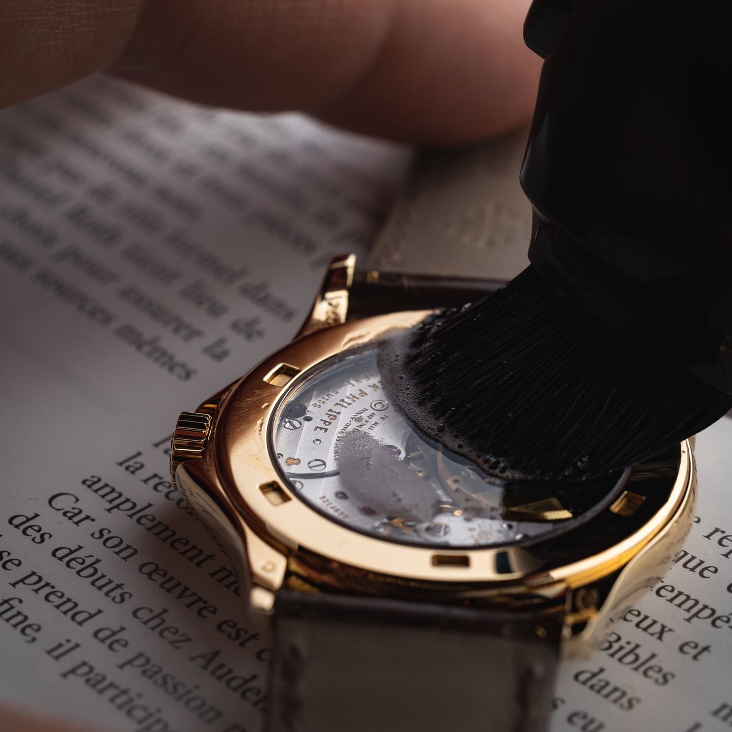 Safely wiping and polishing the case back of a luxury gold watch using the premium microfiber cloth from the AIS Collective Watch Care Kit.