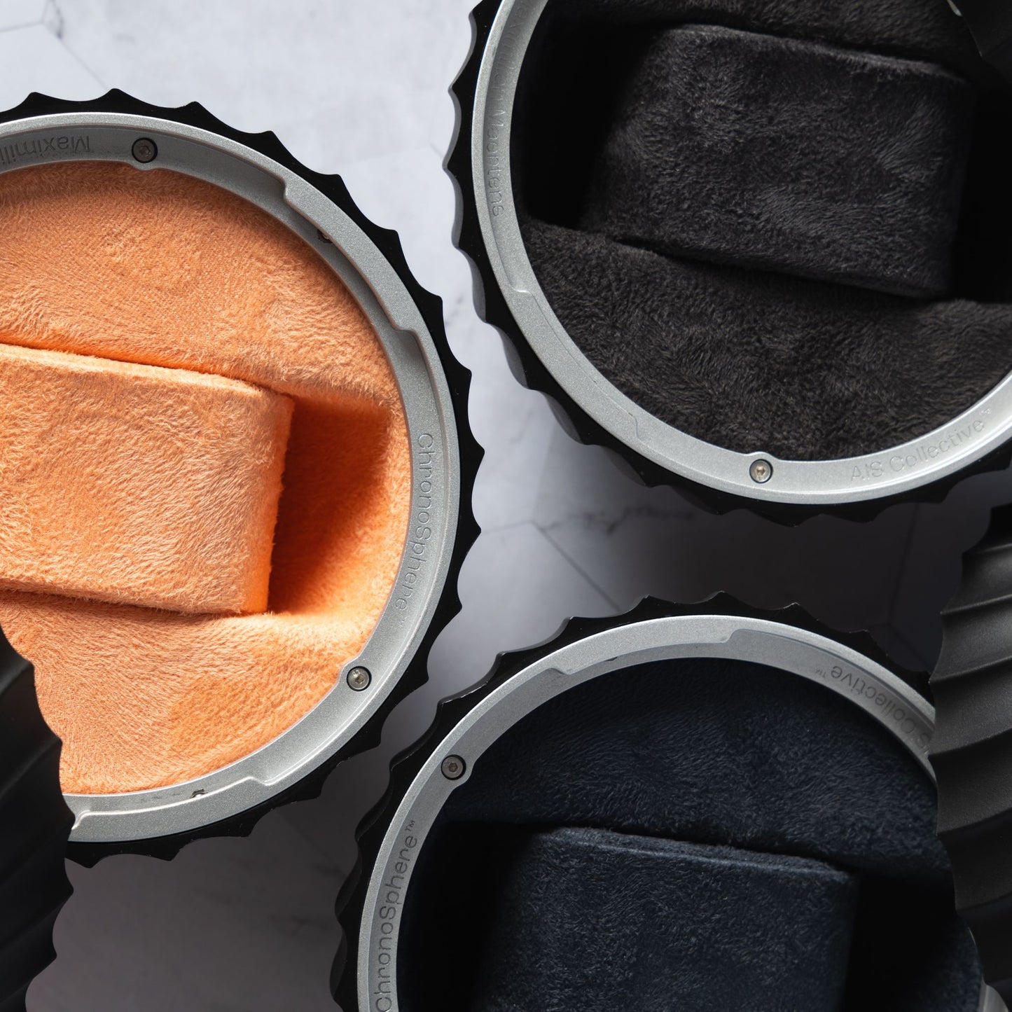 Overhead view of three AIS Collective ChronoSphere luxury watch cases in Salmon, Obsidian Black, and Graphite Blue.