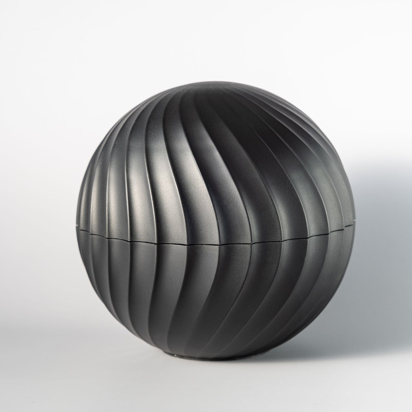 The closed matte black ChronoSphere watch container featuring a minimalist, ribbed Swiss design.